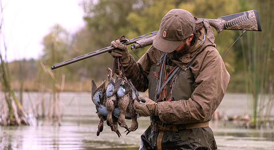 hunter holding shotgun and ducks